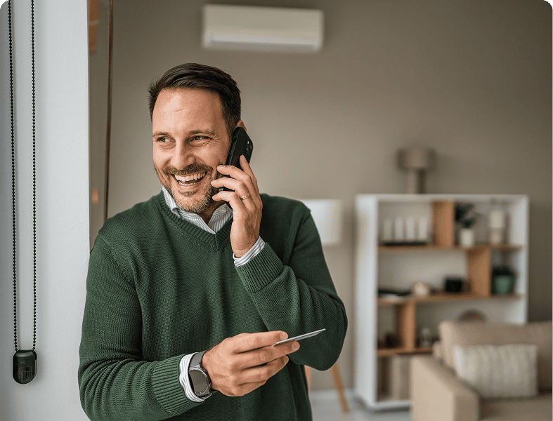 Man talking on phone, smiling, holding card.