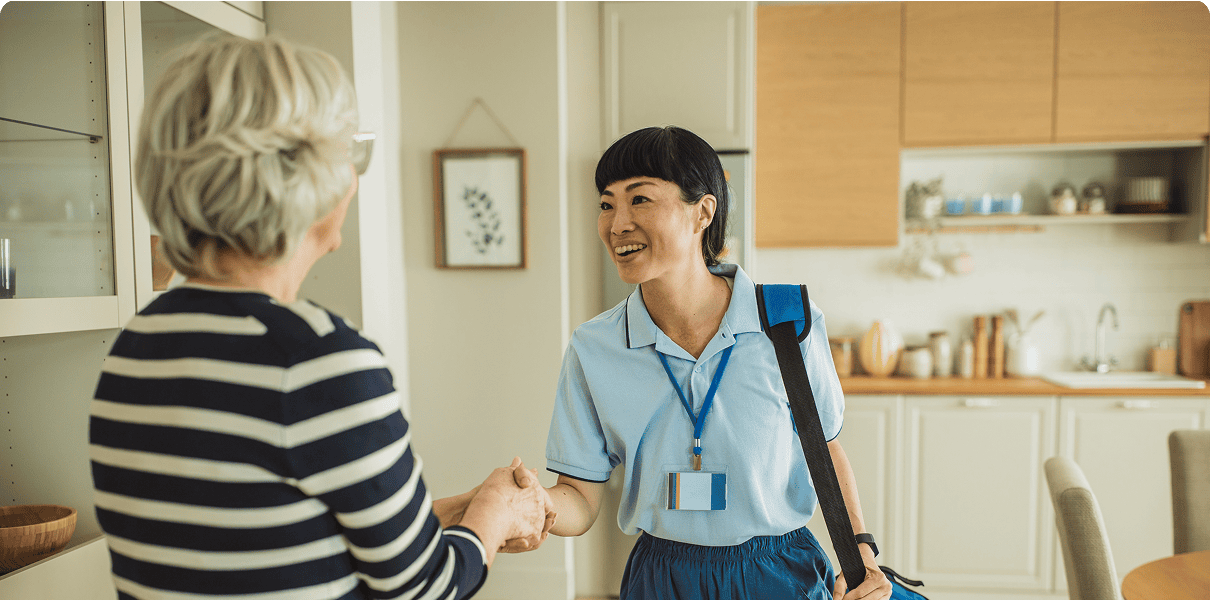 Healthcare worker greeting elderly woman at home.