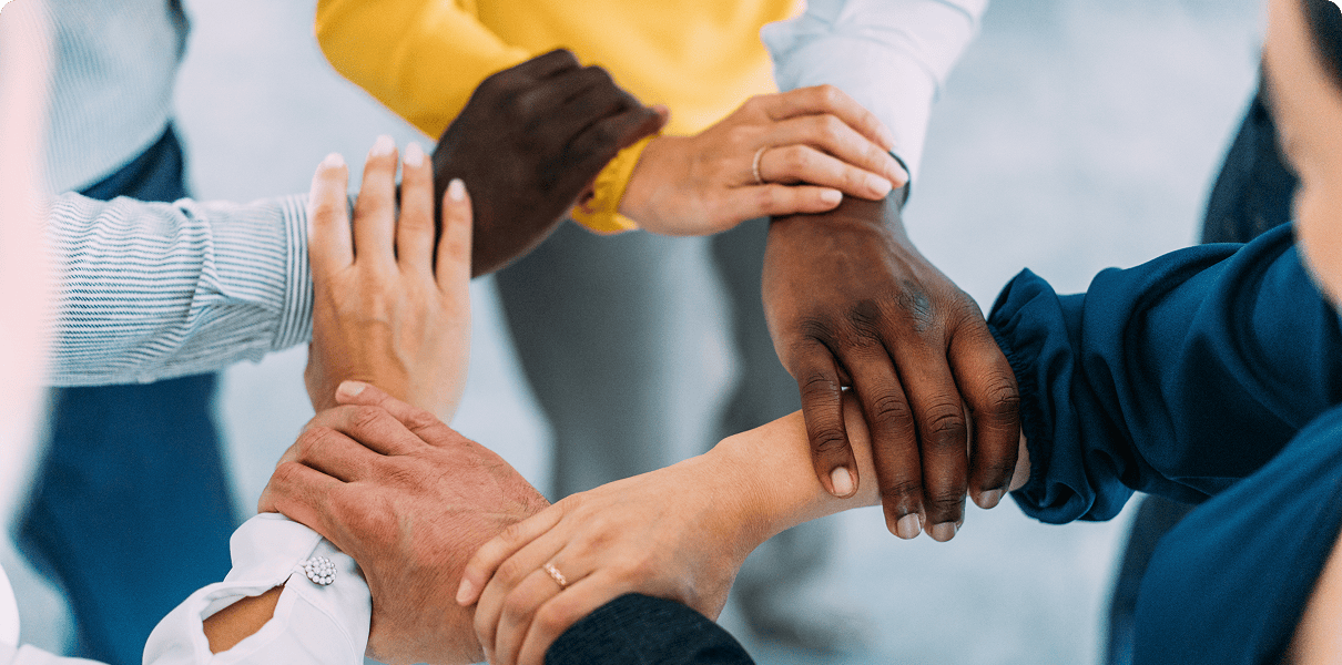 Diverse hands joined in a supportive circle.